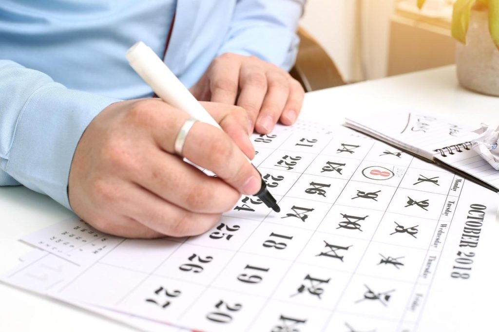 画像：カレンダーにばつ印を書き込む人